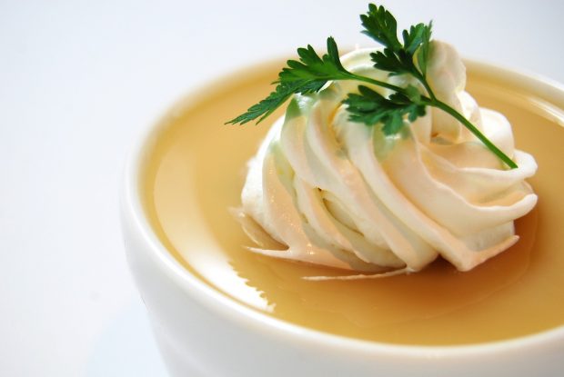 Carrot soup with whipped cream topping and parsely garnish