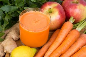 Glass of carrot juice plus carrots and apples